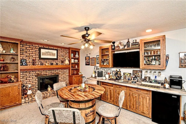 kitchen featuring light carpet, refrigerator, ceiling fan, a fireplace, and a textured ceiling