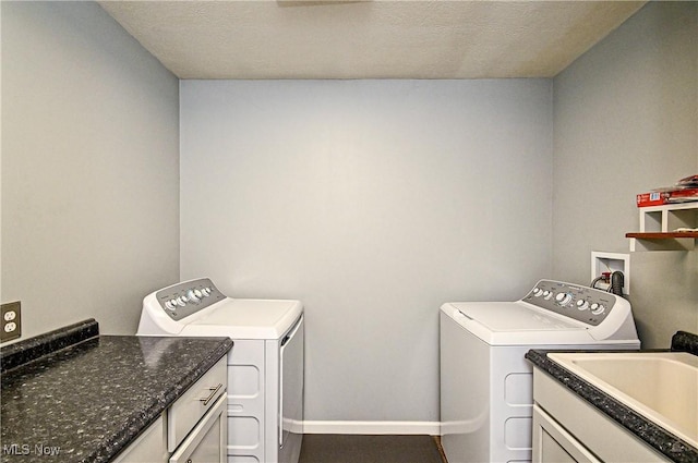 laundry area featuring a textured ceiling, washing machine and dryer, cabinets, and sink