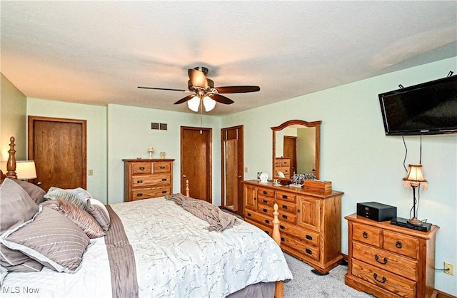 carpeted bedroom featuring multiple closets, ceiling fan, and a textured ceiling