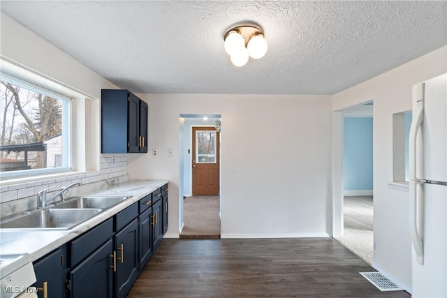 kitchen featuring blue cabinetry, sink, dark hardwood / wood-style floors, white refrigerator, and decorative backsplash