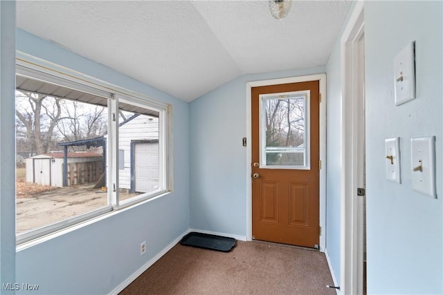 entryway featuring carpet, a textured ceiling, and vaulted ceiling