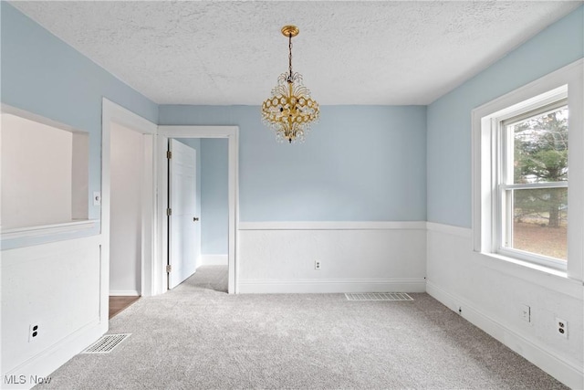 empty room with a chandelier, a healthy amount of sunlight, and a textured ceiling