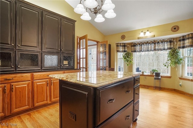 kitchen with dark brown cabinets, a notable chandelier, a center island, light hardwood / wood-style floors, and lofted ceiling