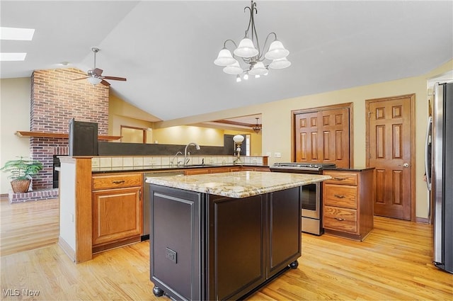 kitchen with kitchen peninsula, appliances with stainless steel finishes, a kitchen island, and light stone countertops