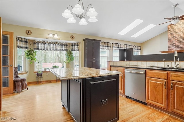 kitchen with stainless steel dishwasher, ceiling fan with notable chandelier, sink, light hardwood / wood-style flooring, and a center island