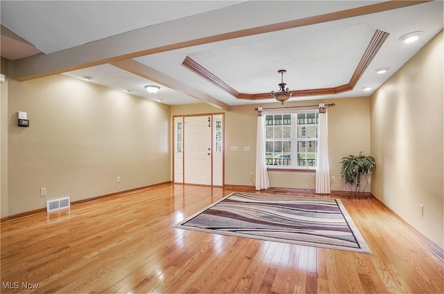 interior space featuring a raised ceiling, light hardwood / wood-style flooring, and ornamental molding