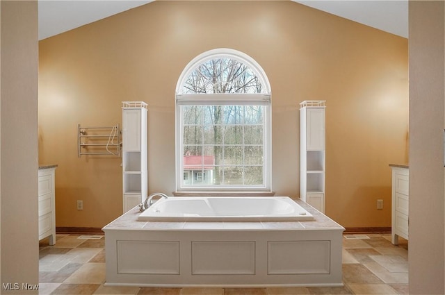 bathroom featuring a bathing tub, vanity, and lofted ceiling