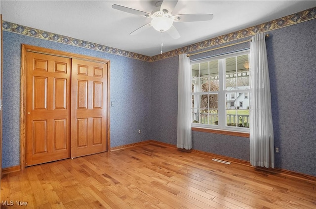 unfurnished bedroom with ceiling fan, a closet, and light hardwood / wood-style floors