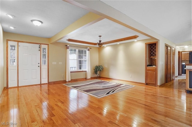 foyer entrance featuring light hardwood / wood-style floors and a tray ceiling