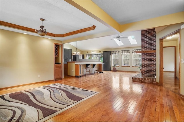 unfurnished living room with lofted ceiling, ceiling fan with notable chandelier, and light wood-type flooring