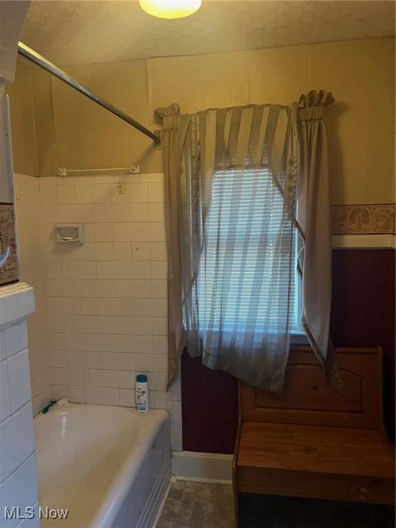 bathroom featuring a wealth of natural light and tiled shower / bath