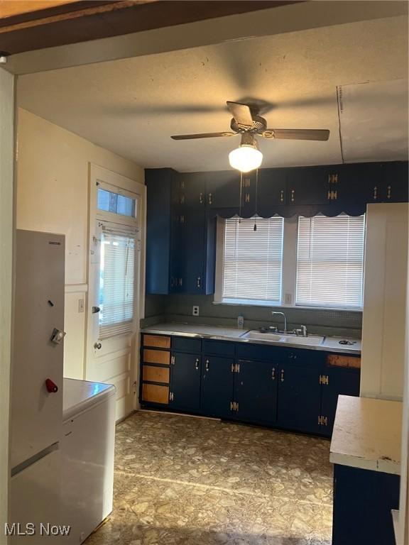 kitchen featuring blue cabinetry, ceiling fan, and sink