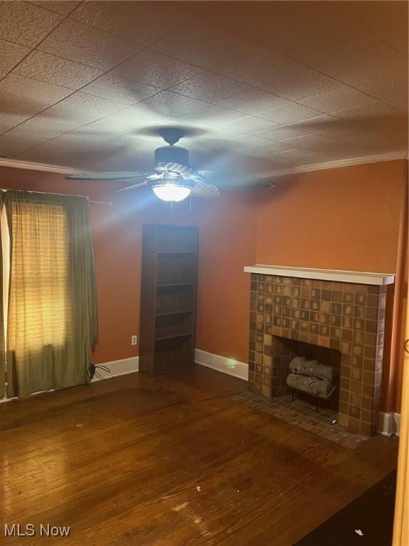 unfurnished living room with hardwood / wood-style floors, ornamental molding, and a tile fireplace