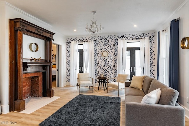 living room featuring crown molding, french doors, light hardwood / wood-style floors, and an inviting chandelier