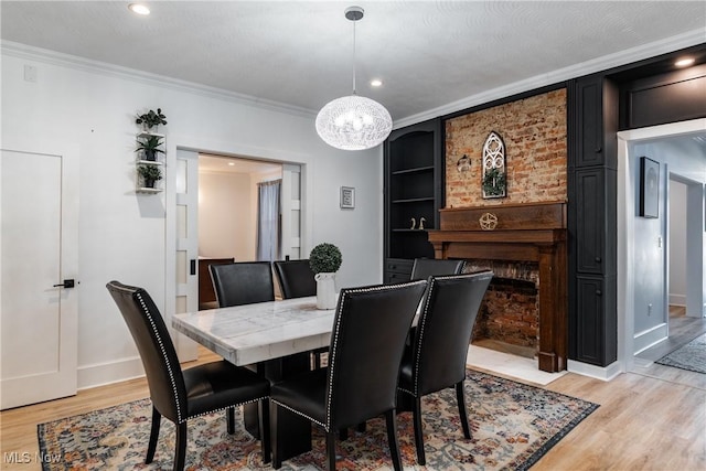 dining area featuring ornamental molding, a textured ceiling, a chandelier, a fireplace, and light hardwood / wood-style floors