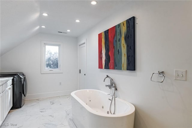 bathroom featuring vanity, a bath, lofted ceiling, and washer / dryer