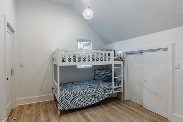 bedroom featuring hardwood / wood-style floors, a closet, and lofted ceiling