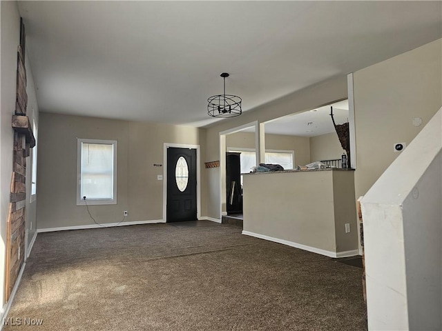 entrance foyer featuring a chandelier and dark carpet