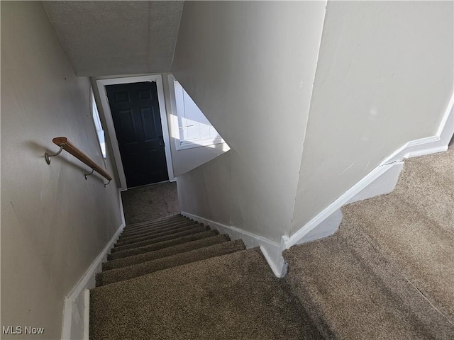 stairway with carpet, a textured ceiling, and lofted ceiling