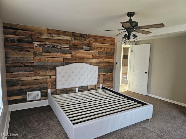 unfurnished bedroom with carpet flooring, wood walls, and ceiling fan