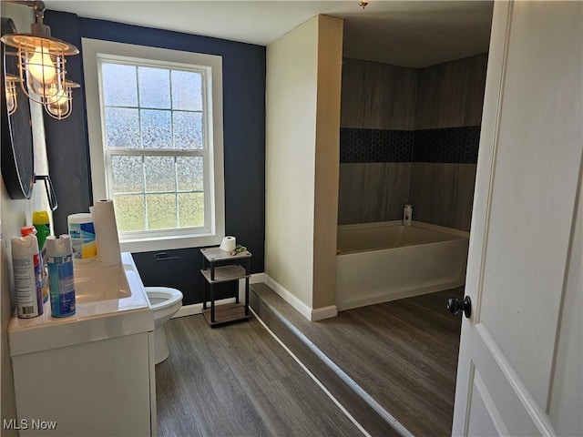 bathroom with plenty of natural light, toilet, wood-type flooring, and vanity