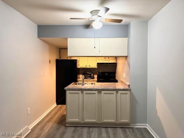 kitchen featuring ceiling fan, sink, dark wood-type flooring, kitchen peninsula, and black appliances