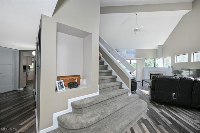 stairs featuring ceiling fan, high vaulted ceiling, and wood-type flooring