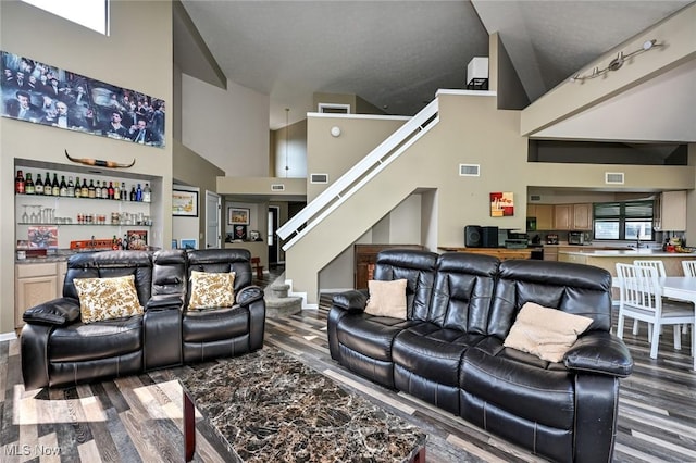 living room featuring hardwood / wood-style floors, high vaulted ceiling, and bar