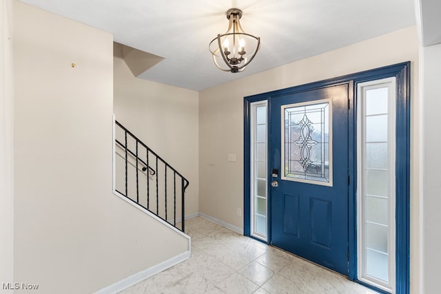 foyer with baseboards, stairway, and a chandelier