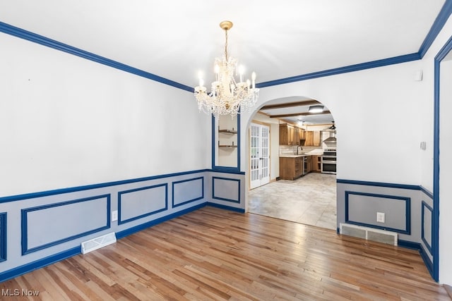 unfurnished dining area featuring crown molding, sink, light hardwood / wood-style floors, and a notable chandelier