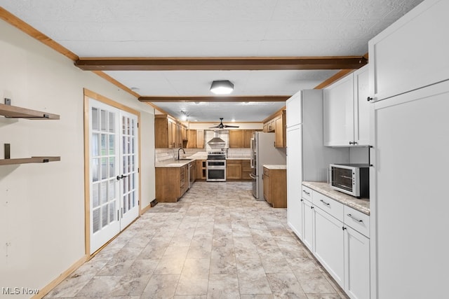 kitchen featuring stainless steel appliances, brown cabinets, a sink, and beamed ceiling