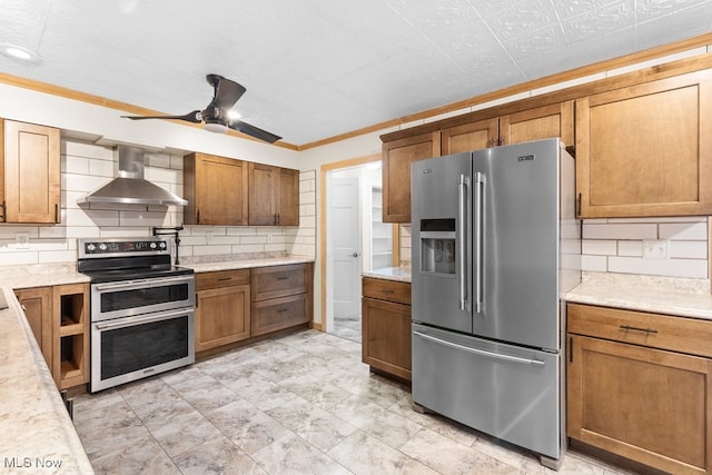 kitchen featuring stainless steel appliances, light countertops, wall chimney range hood, and decorative backsplash