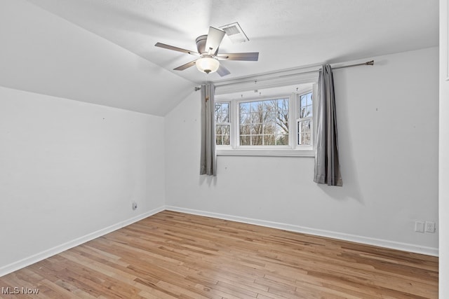 additional living space featuring lofted ceiling, a ceiling fan, visible vents, baseboards, and light wood finished floors