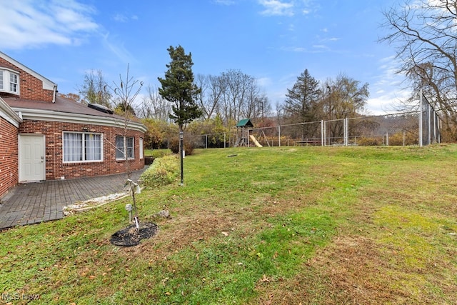 view of yard featuring a playground, fence, and a patio