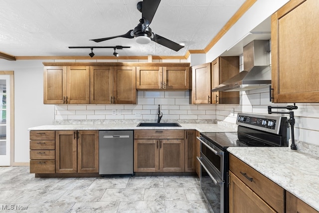 kitchen featuring tasteful backsplash, a ceiling fan, appliances with stainless steel finishes, wall chimney range hood, and a sink