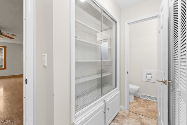 bathroom with toilet, ceiling fan, visible vents, and baseboards