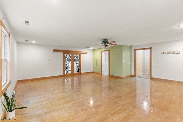 spare room with a ceiling fan, visible vents, light wood-style flooring, and baseboards