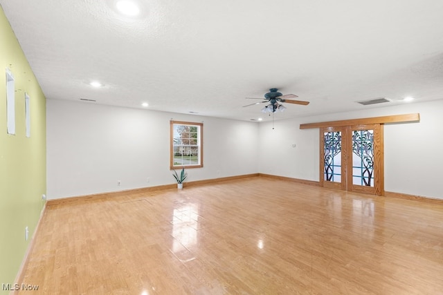 empty room with light wood finished floors, a ceiling fan, baseboards, and a textured ceiling