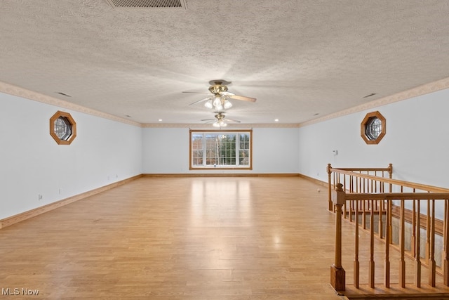 unfurnished room featuring light wood-type flooring, visible vents, a textured ceiling, and baseboards