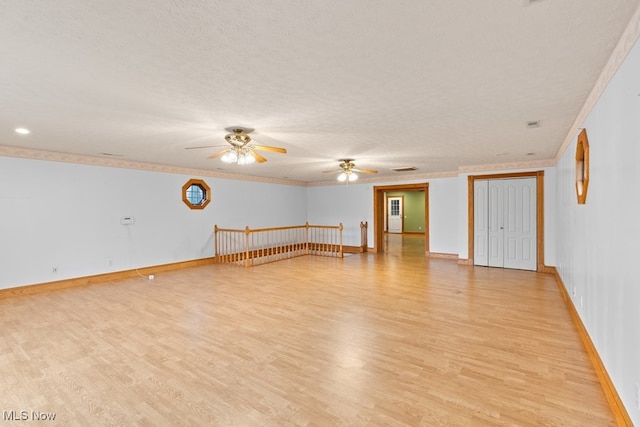 spare room with a textured ceiling, light hardwood / wood-style floors, ceiling fan, and ornamental molding