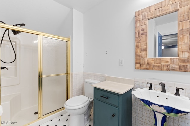 bathroom featuring a sink, a shower stall, toilet, and tile walls