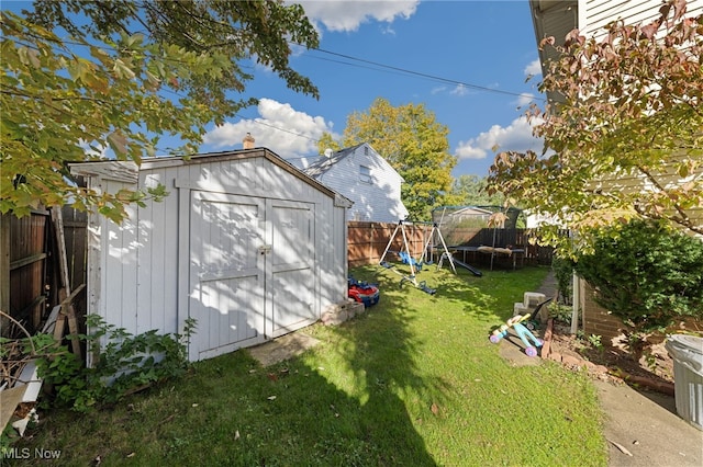 view of outbuilding featuring a playground, a yard, and a trampoline