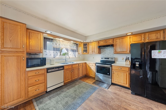 kitchen featuring black appliances, backsplash, sink, and light hardwood / wood-style flooring