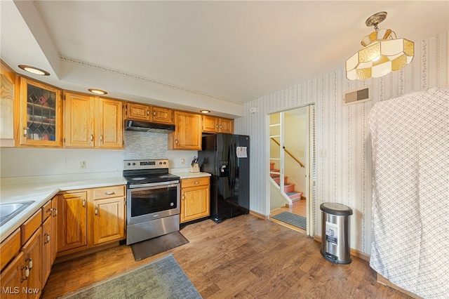 kitchen with stainless steel range with electric stovetop, black fridge with ice dispenser, hanging light fixtures, and hardwood / wood-style flooring