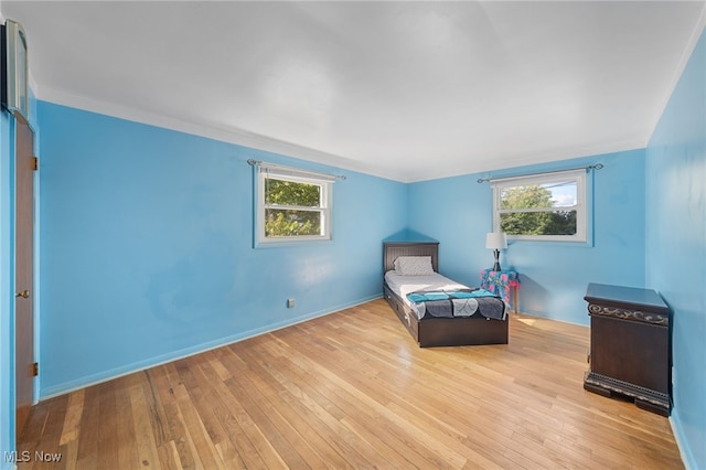 bedroom featuring light hardwood / wood-style floors, multiple windows, and crown molding