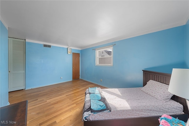 bedroom featuring hardwood / wood-style floors, crown molding, and a closet