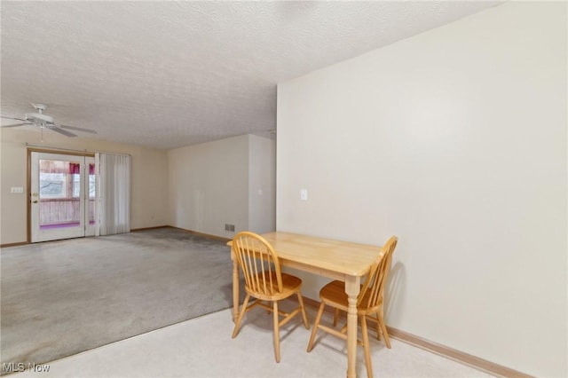 carpeted dining room with a textured ceiling and ceiling fan