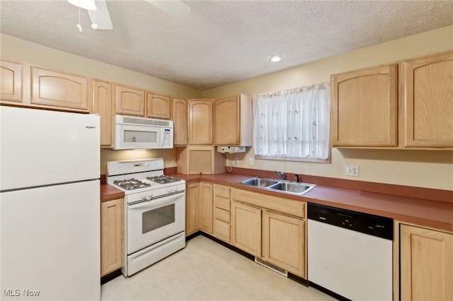 kitchen with light brown cabinets, white appliances, and sink