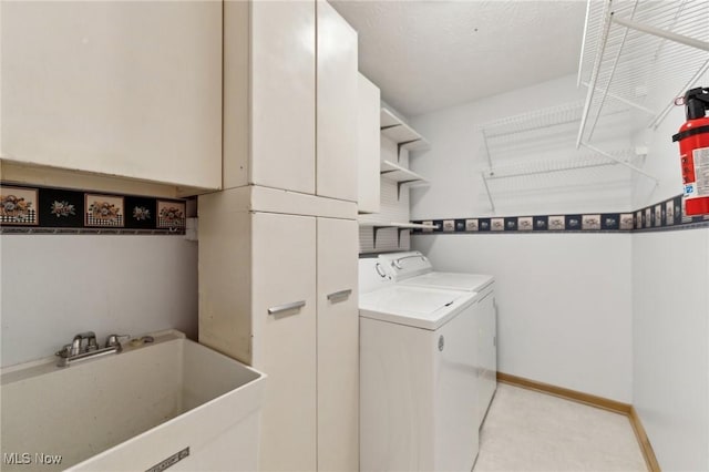 laundry room featuring cabinets, independent washer and dryer, and sink