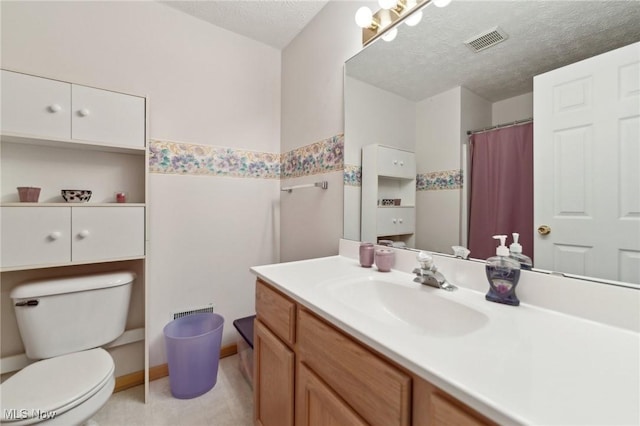 bathroom with vanity, toilet, and a textured ceiling